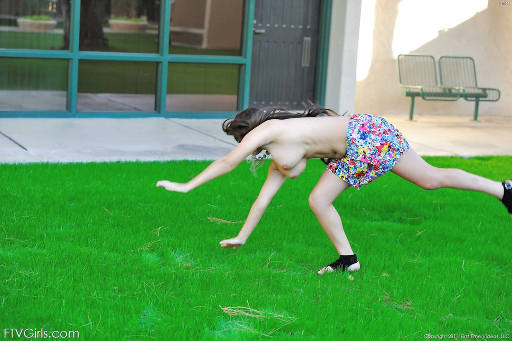 Leila does cartwheels topless outside.