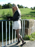 Gorgeous blonde Erin is outdoors showing off her shiny legs covered in silky nylon and her beautiful black stilettos