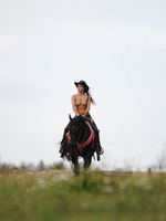 Brunette model Kristina rides a black horse