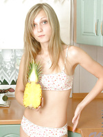 Long haired teen blonde posing and playing with toy fruit in the kitchen
