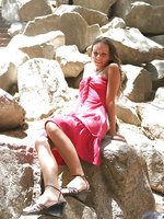 Sexy teen sits out on some rocks in the shadows in her pink prom like dress so sexy