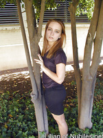Redhead in a short black dress climbs a tree