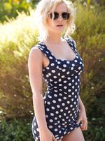 pulls down her polka dot dress under the glowing sun